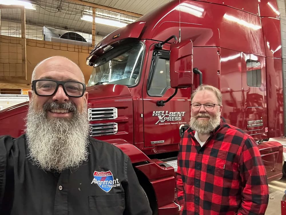 Two men smiling in front of a red truck.